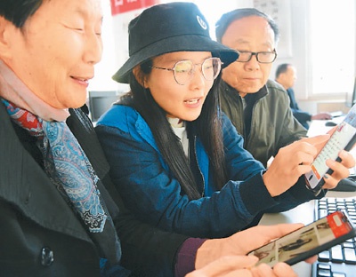 江苏科技大学志愿者在指导老年人学习使用智能手机上网购物的技能。 石玉成摄(人民图片)