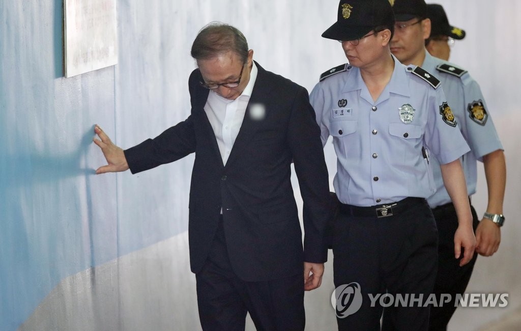 27日,李明博出庭受审,扶墙走路.(韩联社)