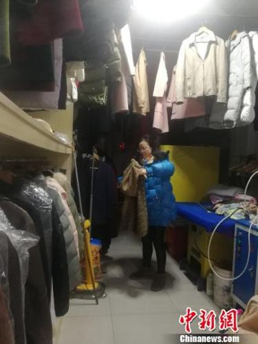 2月22日，经营洗衣店的王芳在整理已经清洗好的衣服。　苏路程 摄