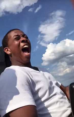 男子挑战乘坐过山车脸颊被风拍打致表情夸张