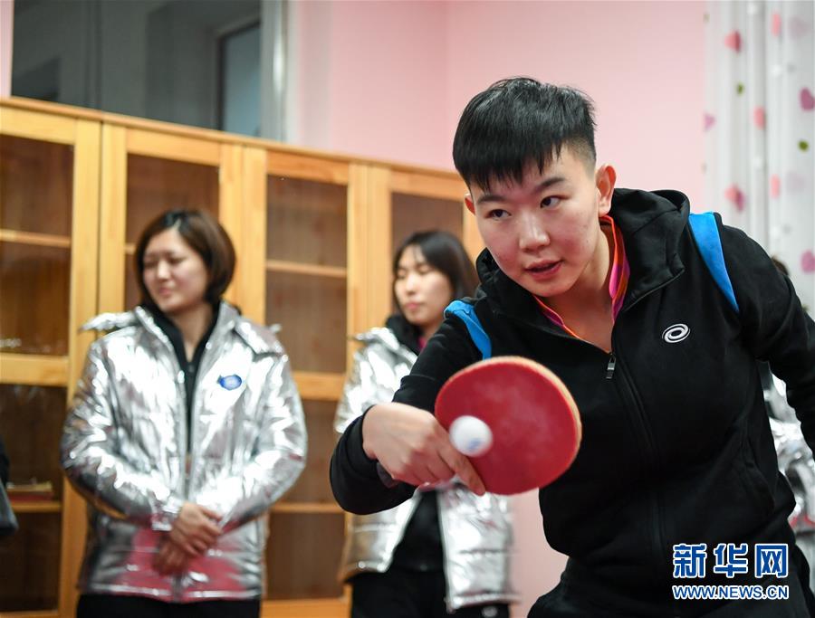 中州电缆永刚俱乐部球员刘铭(前)与哈尔滨市公园小学校的学生打乒乓球