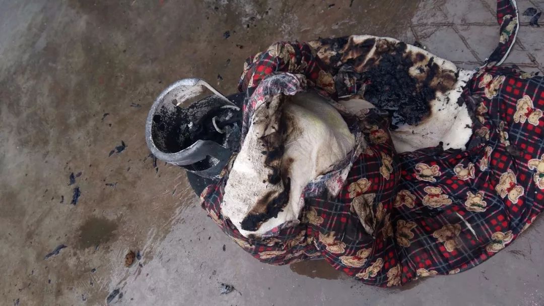 图为专职消防队员用棉被将燃烧的钢瓶包起,扛到室将火扑灭后的情景