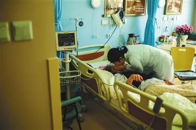 北京大学首钢医院安宁疗护中心,因为老人耳背,医护人员需要趴在老人耳边才能和老人交流。摄影/新京报记者 彭子洋