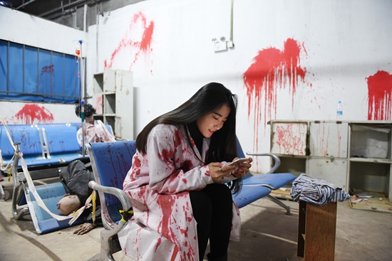 一家惊悚主题屋"丧尸医院"里,"惊吓师"吉林女孩周昕昕在工作间歇玩
