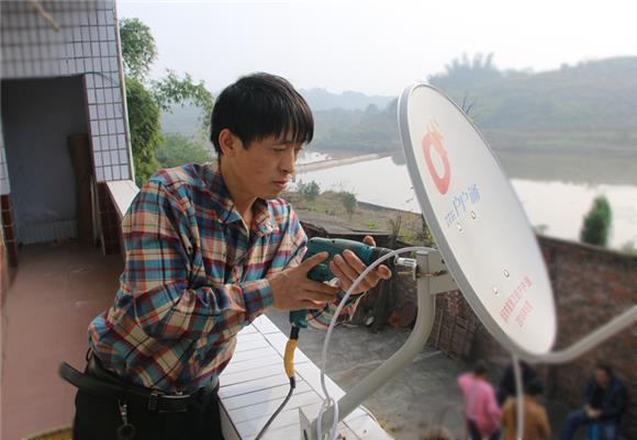 驻村工作队队员为村民安装调试"户户通"设备.