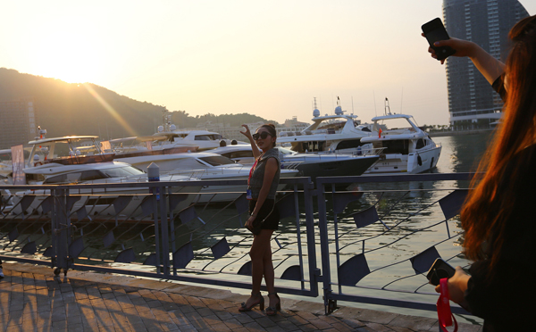 2017年12月8日,海南三亚,参观者在展出的游艇旁拍照留念.