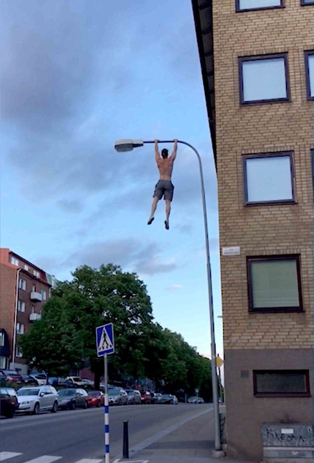 瑞典消防员赤膊爬上路灯杆表演引体向上