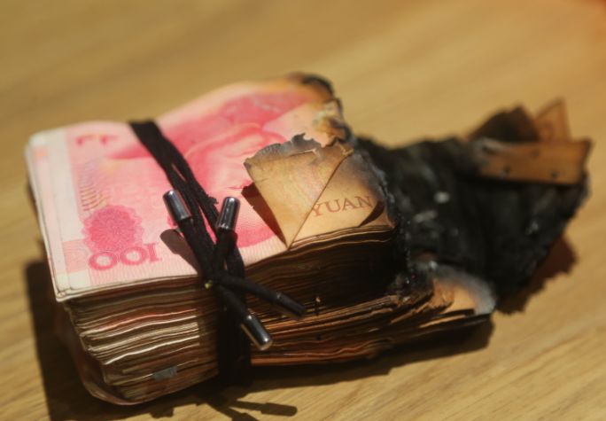当从灶坑的垃圾堆中找出钱袋子时,捆好的那一沓人民币烧得只剩下半截