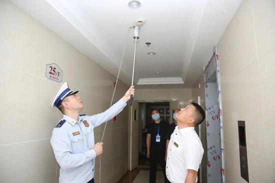 消防检查人员来到37幢一单元25楼,利用感烟探测器测试烟枪检测感烟
