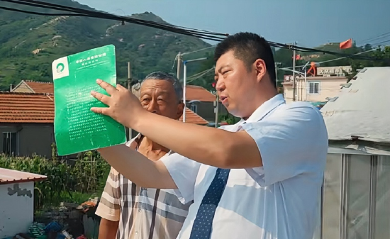 （图：姜东军为岛上居民讲解保险业务）